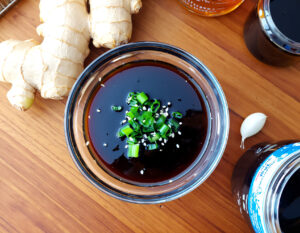 Oil-Free Teriyaki Sauce in a glass bowl with green onions and sesame seeds, healthy vegan sauce