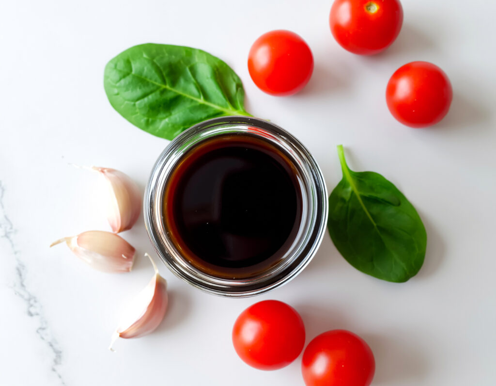Glass jar of oil-free balsamic vinaigrette on marble with greens